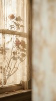 Soft morning sunlight filters through lace curtains casting delicate plant shadows on window sill creating warm peaceful atmosphere for home decor and relaxation.