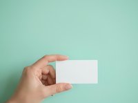Hand holding blank white business card against mint green background for branding and corporate identity design projects.