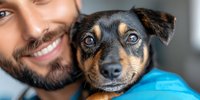 Smiling bearded man hugging miniature pinscher mix dog with expressive eyes. Close up portrait showing bond between pet owner and companion animal.