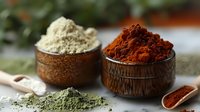 Colorful spice powders in wooden bowls - red paprika, yellow turmeric and green matcha tea powder. Natural cooking ingredients on dark background.