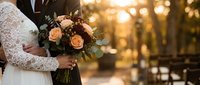 Bride and groom holding wedding bouquet with roses during golden hour ceremony. Romantic couple celebration with warm sunlight bokeh background.