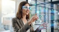 Professional businesswoman in suit using augmented reality smart glasses to interact with holographic data visualization and digital interface in modern office.