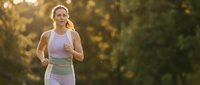 Young athletic Caucasian woman jogging outdoors in purple sportswear during golden hour sunset with warm natural lighting and bokeh background.