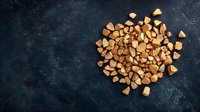 Crunchy golden freeze-dried coffee granules scattered on dark textured background, perfect for food and beverage advertising.