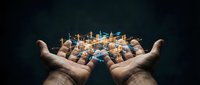 Hands holding glowing cityscape hologram against dark background, representing urban development, smart city technology, and future infrastructure planning.