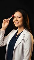 Smiling female doctor or medical professional holding red pen near forehead in white coat against black background for healthcare marketing materials.