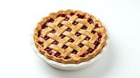 Homemade berry pie with golden lattice crust in white ceramic dish, isolated on white background for bakery, recipe, and food design projects.