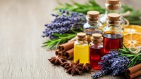 Essential oils in glass bottles with lavender, cinnamon, star anise and dried orange slices for aromatherapy and natural wellness treatments.