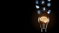 Glowing light bulb with brain filament and floating technology icons on dark background representing innovation and creative thinking in business.