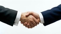 Two businessmen in suits shaking hands, symbolizing agreement, partnership, and professional trust in a corporate setting.