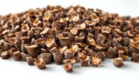 Dried organic shiitake mushroom pieces scattered on white surface, macro food photography showing natural texture and earthy brown colors for culinary design.