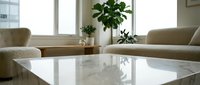 Modern minimalist living room interior with white marble coffee table, beige sofas, and green plants by large windows creating bright natural lighting.