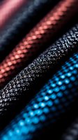Macro shot of textured fabric with vibrant blue, pink and black colors showing detailed weave pattern and textile surface structure in dramatic lighting.