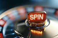 Illuminated red spin button on casino gaming machine wheel, close-up view with selective focus and reflection showing entertainment atmosphere.