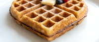 Golden waffle with butter and blueberries on white plate, breakfast food for culinary, bakery, and restaurant design projects.