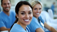 Healthcare professionals in blue scrubs smiling at camera, diverse medical team in hospital setting showing positive workplace environment and teamwork.
