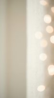 Soft beige background with warm golden bokeh lights creating dreamy atmosphere for holiday celebrations, wedding events, and festive decorations.