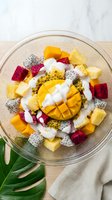 Colorful tropical fruit bowl with mango, dragon fruit, pineapple and coconut yogurt on wooden table for healthy breakfast and summer dining concepts.