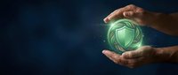 Hands holding glowing green shield symbol representing cybersecurity, data protection, and digital safety for technology and business concepts.