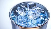 Refreshing ice cubes with blue tint in metal cup, creating cool atmosphere for beverages and cocktails at summer parties or restaurant settings.