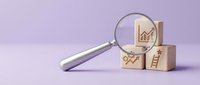 Business growth analysis concept with magnifying glass examining wooden blocks featuring upward arrow chart, percentage and ladder symbols on purple background.