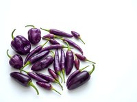 Purple eggplants with green stems arranged on white background, suitable for food, cooking, recipe, and culinary design projects.
