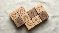 Wooden rubber stamps with celestial and nature symbols including sun, moon, stars and leaves arranged on textured surface for crafting projects.