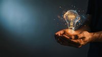 Businessman holding glowing light bulb with sparkling particles, representing innovation, creativity, and bright ideas for business solutions and entrepreneurship.