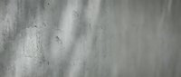 Weathered concrete wall with natural shadows and light patterns creating textured industrial background surface for modern design projects.