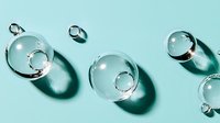 Clear glass spheres and rings scattered on mint green background creating modern minimalist composition with soft shadows for contemporary design projects.