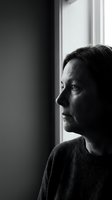Thoughtful middle-aged woman gazing out window in black and white portrait showing contemplation and introspection in natural light for editorial use.