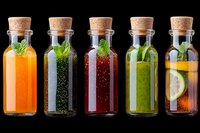 Assortment of fresh detox drinks in glass bottles with cork stoppers, featuring colorful fruit and herb infusions on black background.