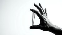 Close-up of a hand holding a small cylindrical object between thumb and fingers against a white background, suitable for healthcare, pharmaceutical, or product demonstration purposes.