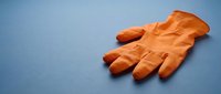 Orange latex glove isolated on blue background, ready for design use in healthcare, safety, cleaning, and medical contexts.