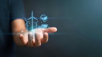 Businessman holding glowing holographic renewable energy icons including wind turbines and solar panels, representing sustainable technology and green power solutions for business.