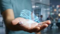 Businessman holding glowing digital brain hologram with neural network connections in modern office environment representing artificial intelligence technology.
