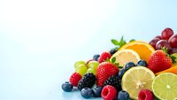 Fresh mixed fruits and berries arrangement with citrus slices on clean white background for healthy eating and nutrition concepts.