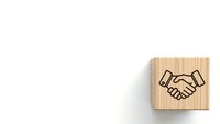 Wooden block with handshake icon on white background representing business partnership, cooperation and agreement concepts for corporate presentations.