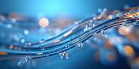 Flowing water waves with floating droplets against blurred blue and orange bokeh background creating dynamic abstract macro composition.