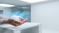 Modern office worker hands holding glowing blue digital wave technology hologram in minimalist white workspace representing data flow and connectivity.