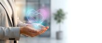 Businesswoman holding glowing heart symbol with digital light effects, representing love, care, and connection in modern corporate environment.