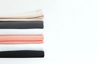 Neatly folded stack of minimal basic cotton t-shirts in neutral and pastel colors on white background. Clean modern fashion flatlay composition.