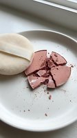Broken pink blush compact with makeup sponge on white plate, cracked cosmetic powder scattered, beauty product accident for skincare and cosmetics content.