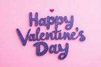 Happy Valentine's Day text in sparkly purple glitter letters with small pink heart on pastel pink background, romantic holiday greeting card style lettering isolated.