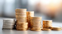 Stacks of golden and silver coins arranged in columns on blurred background representing financial growth, savings, investment and wealth accumulation concept.