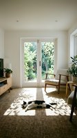 Bright modern living room with French doors opening to garden, featuring mid-century furniture, houseplants, and relaxed cat on textured rug with natural sunlight.