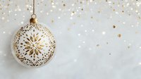 Elegant white and gold Christmas ornament with intricate snowflake pattern hanging against soft bokeh background with golden confetti sparkles.
