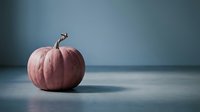 Pink pumpkin on blue surface with moody lighting for autumn seasonal decor and Halloween themes.