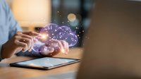 Hands typing on tablet with glowing brain hologram and network connections representing artificial intelligence and digital innovation in modern workspace.