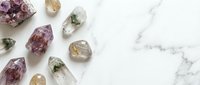 Collection of natural healing crystals and gemstones arranged on white marble surface for wellness meditation and spiritual energy practices.